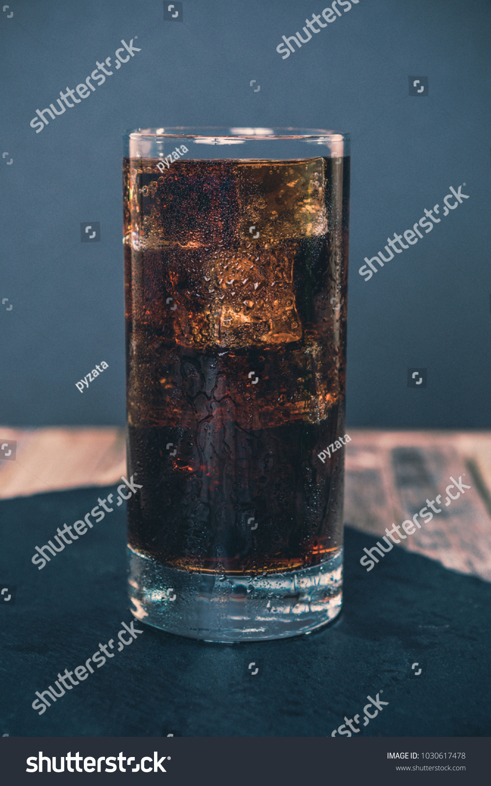 Glass of ice cold cola on dark background