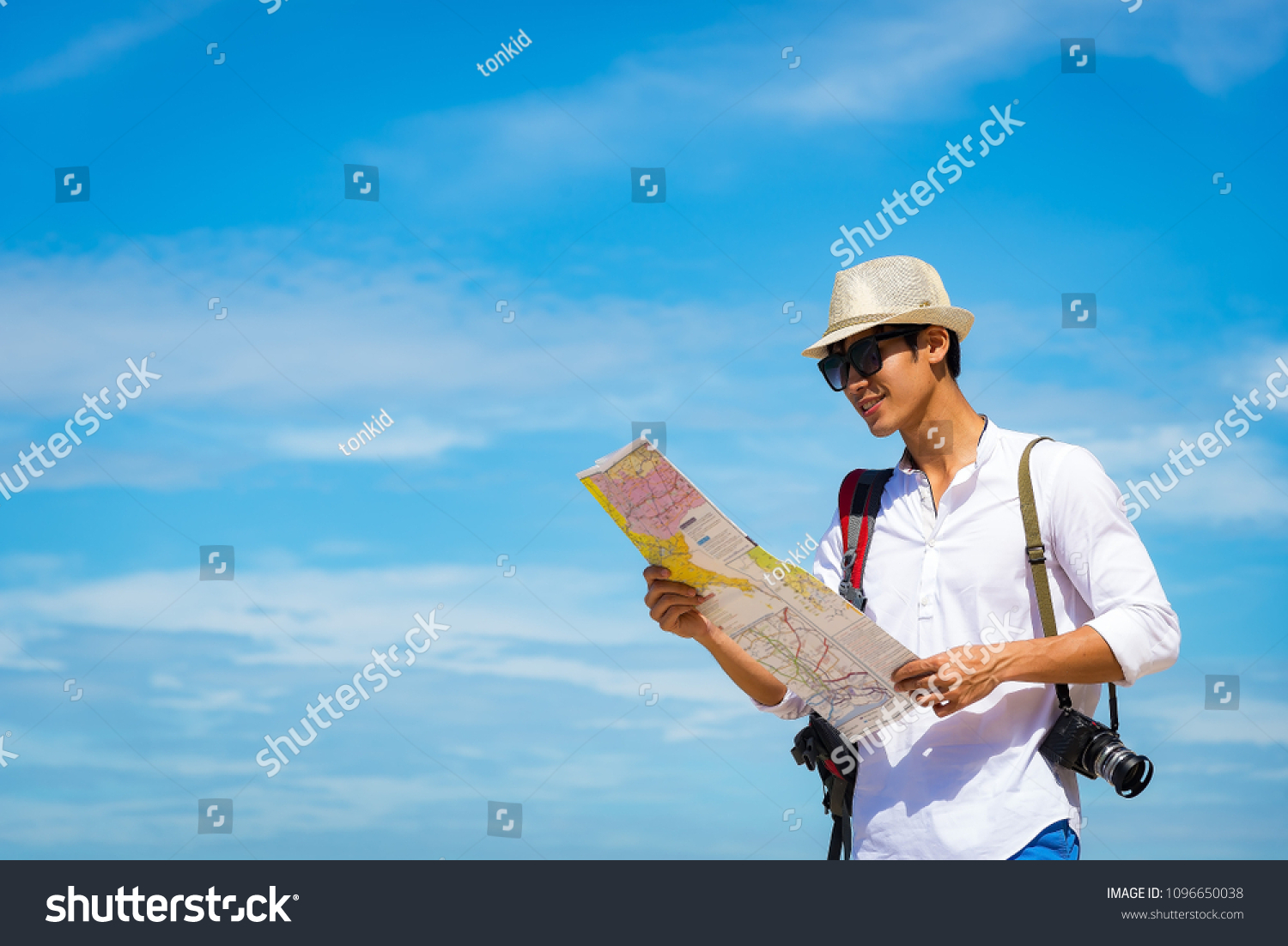 Happy smiling caucasian tourist asian Young Asian man traveler looking maps with camera on the beach. Summer and Travel Concept.