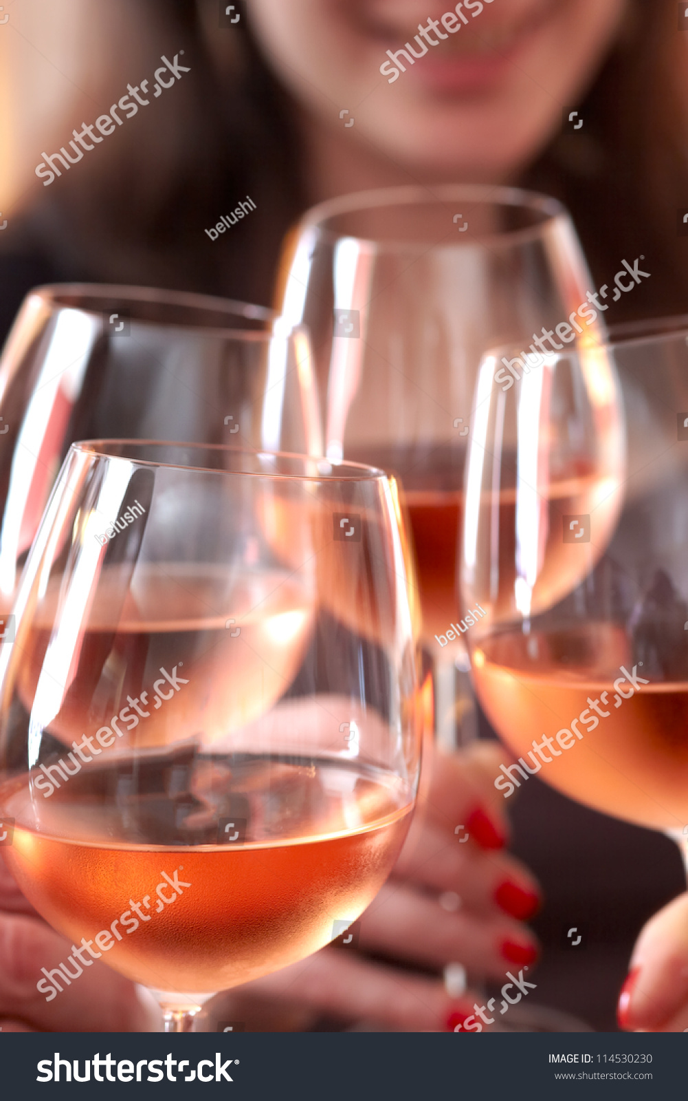 Closeup of four glasses with wine being clinked together during a toast at a celebration