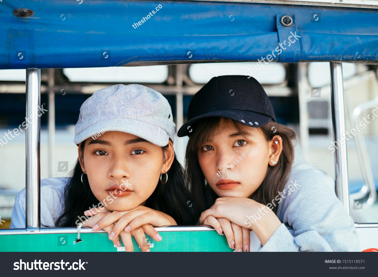 Thai buddy girls sitting on the baht bus their chin rest on their hands looking straight to the camera.