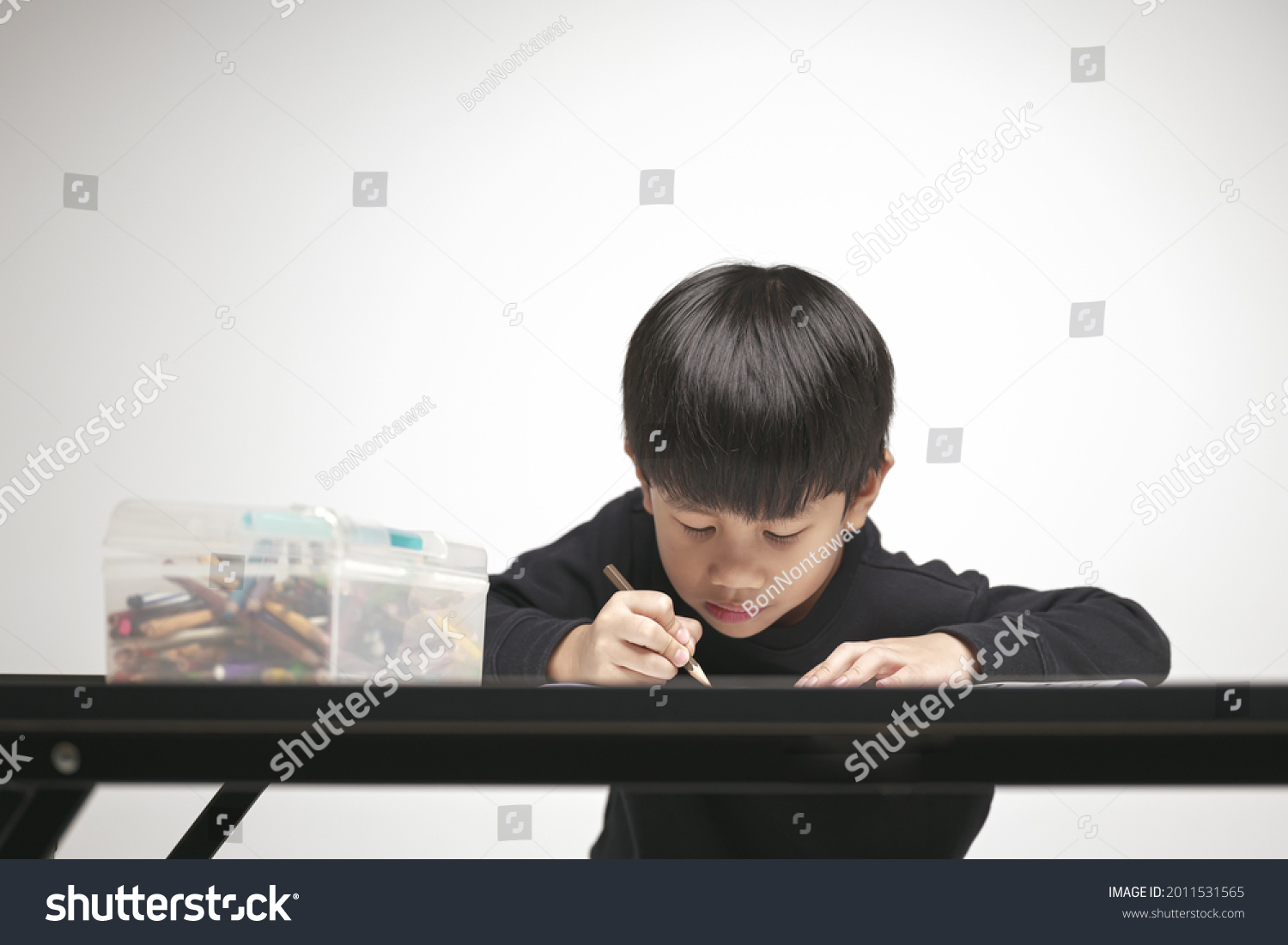 Asian boy about 5 years doing his homework  drawing and painting picture with color pencil.