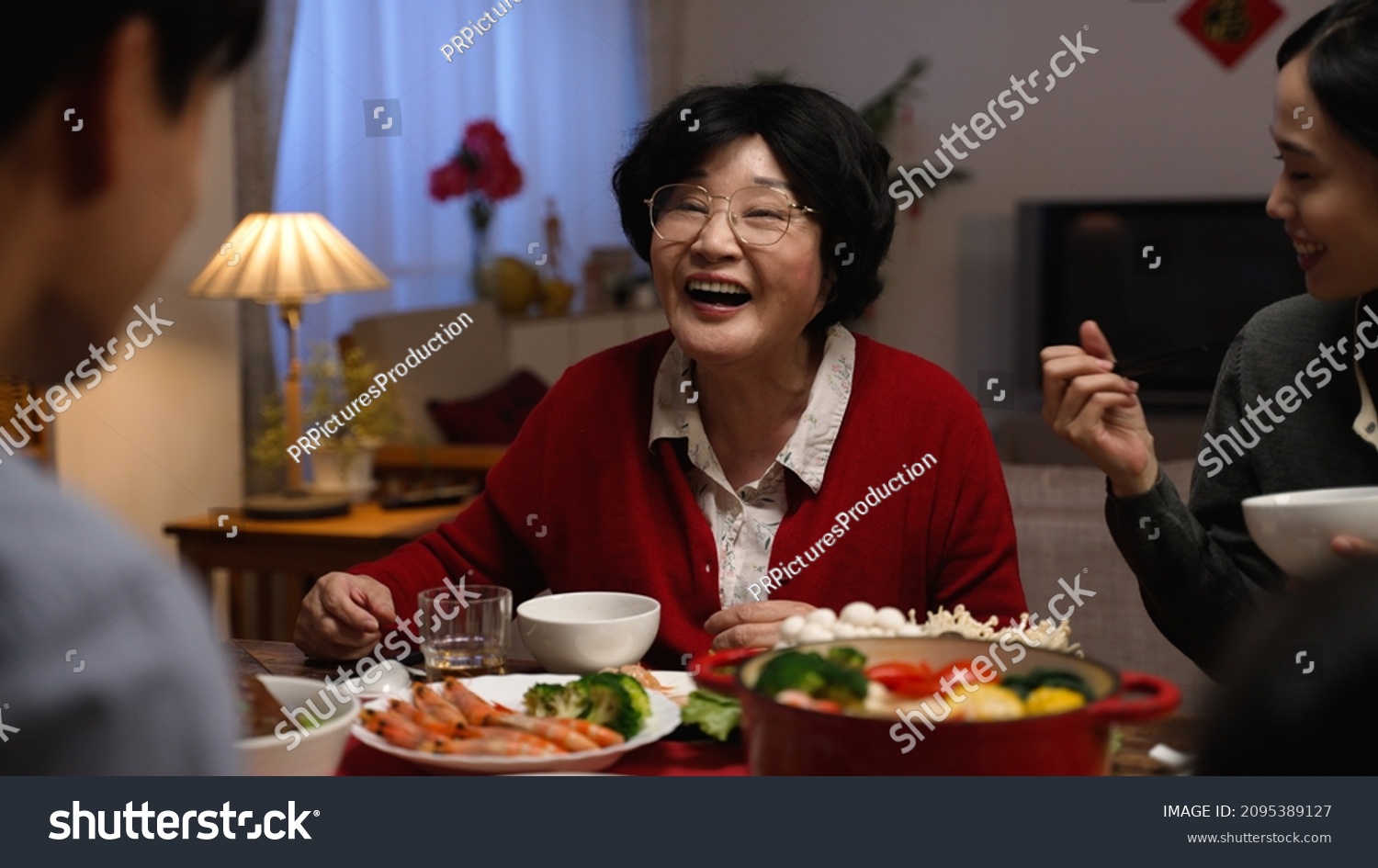 selective focus of a cheerful senior woman grandmother talking with hand gestures while chatting with her adult son at dinner table during family reunion meal at home