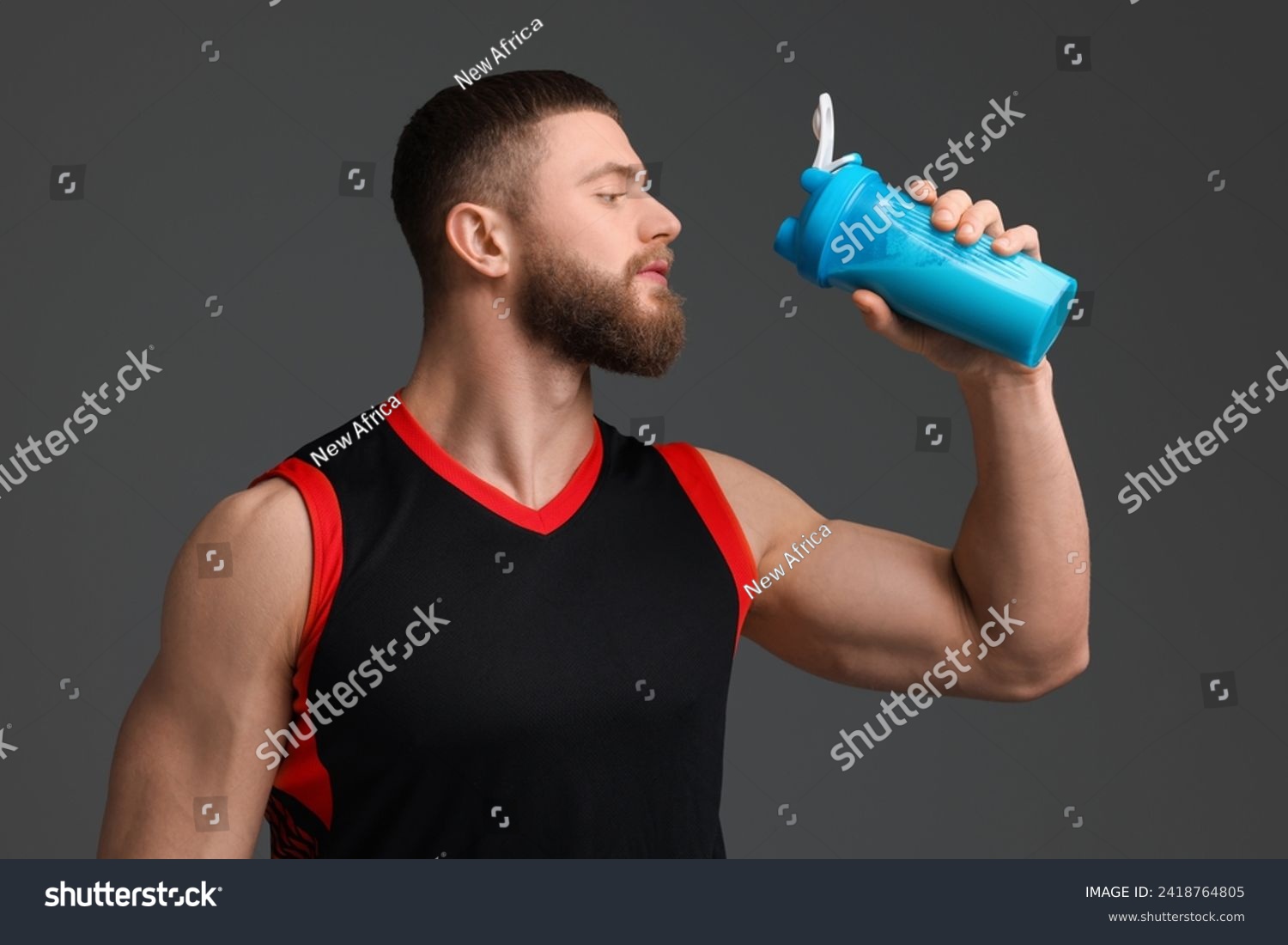 Young man with muscular body holding shaker of protein on grey background