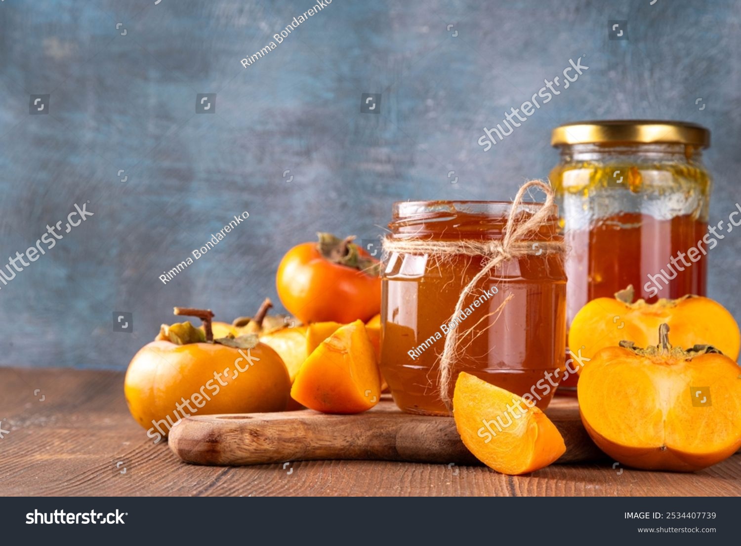 Persimmon jam. Sweet autumn homemade jam or marmalade canning preserves in a jar with whole and cut persimmon c in the background