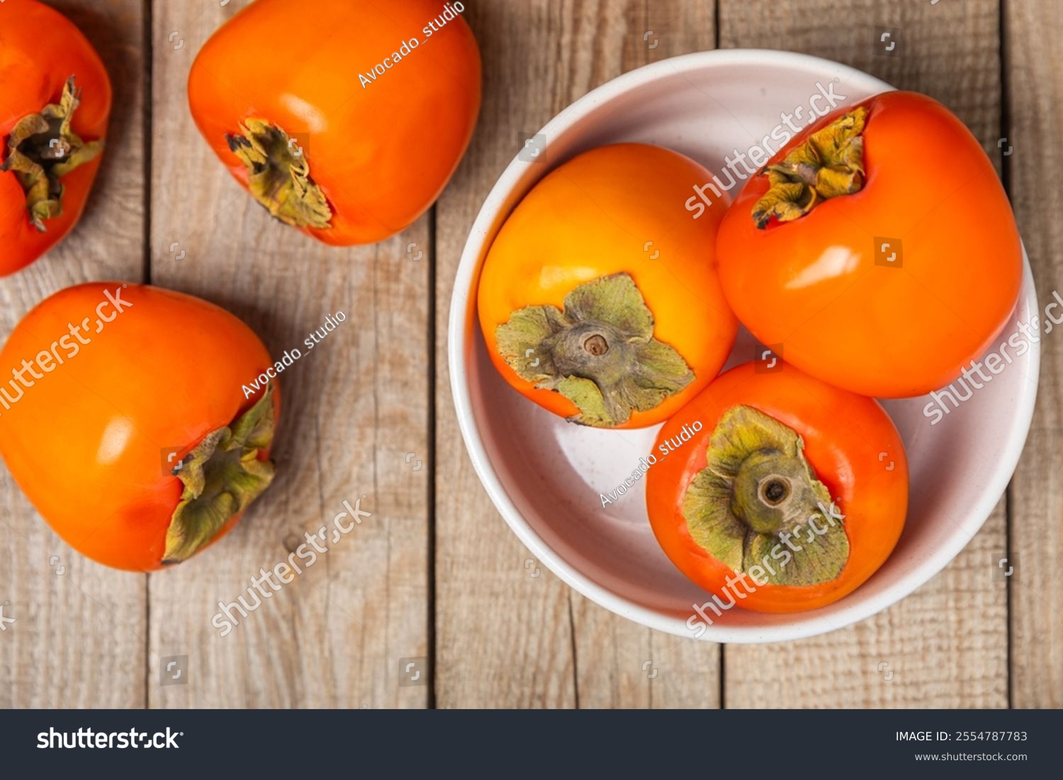 Persimmon on textured wooden background. Persimmon fruit. A piece of ripe juicy sweet persimmon fruit. Vegan. Orchard. Close-up. Space for text. Copy space.