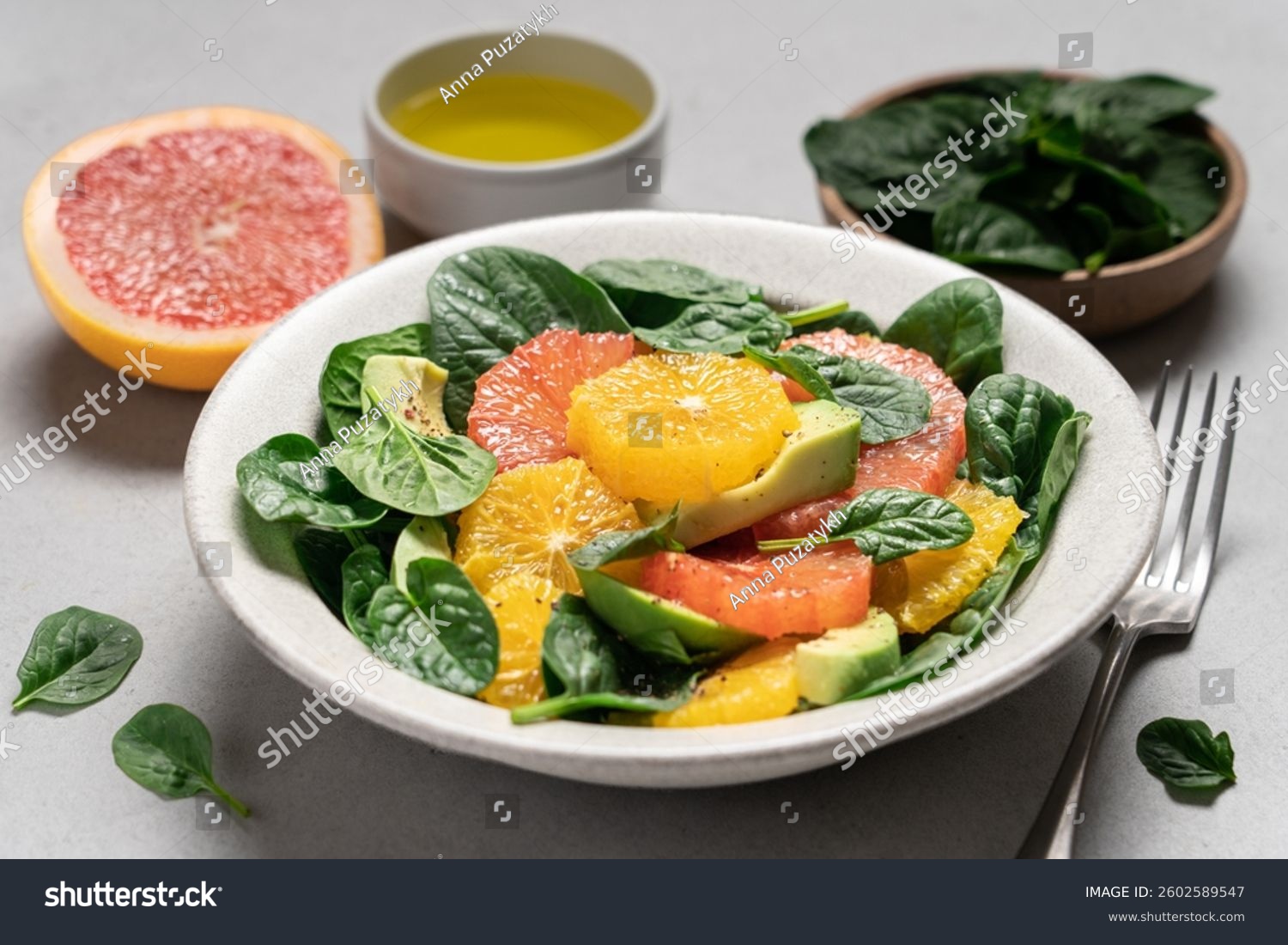 Fresh grapefruit avocado orange spinach salad in bowl. Healthy salad on gray background top view