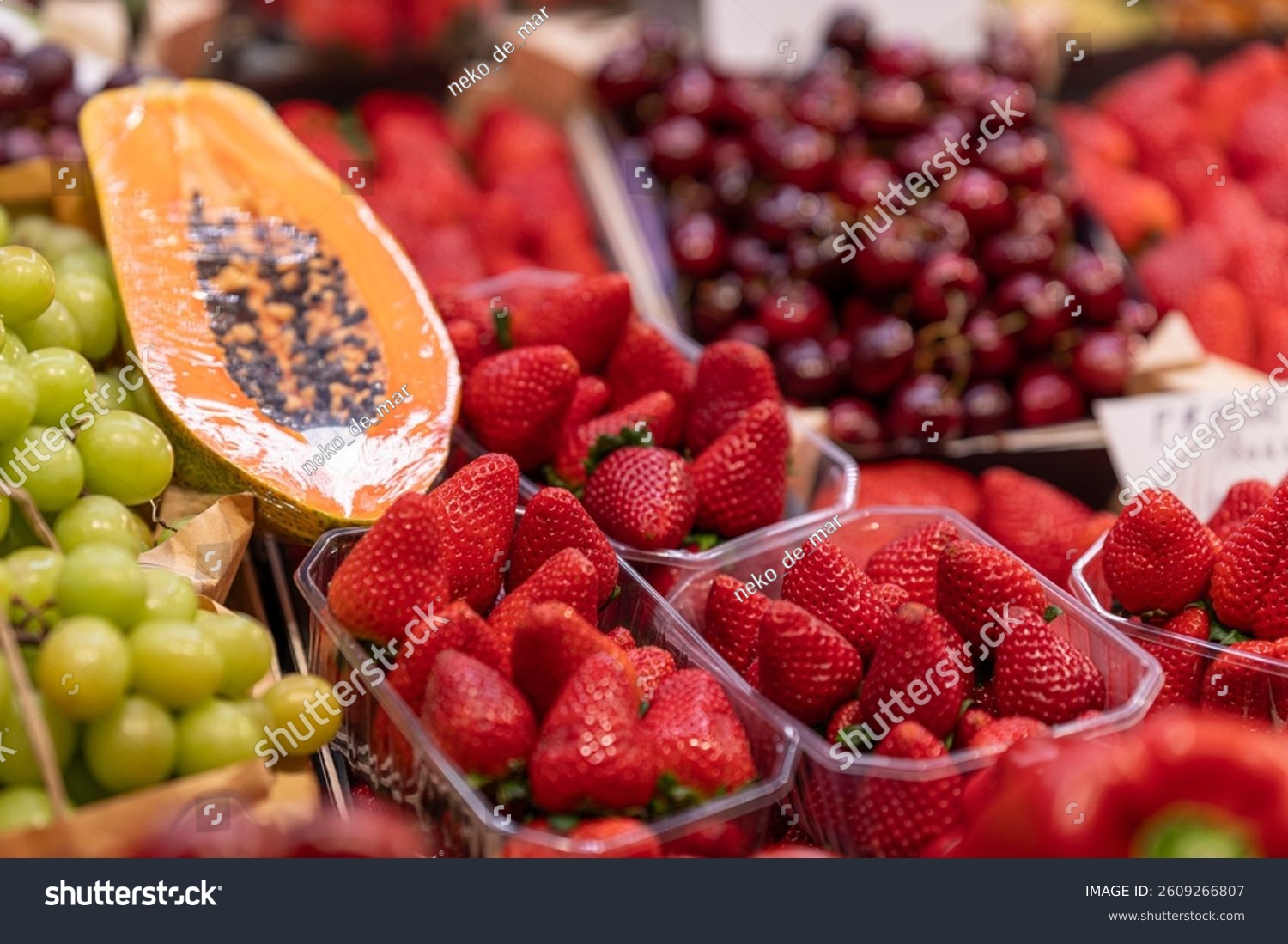 Fresh strawberries grapes cherries and sliced papaya displayed in rustic baskets at a vibrant farmers market showcasing colorful organic and healthy produce.
