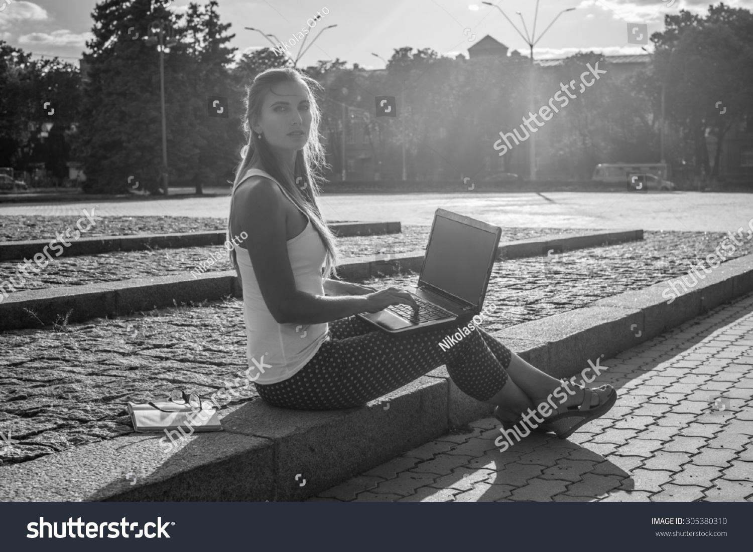Black and White. Young woman using tablet laptop notebook reading books outdoor smiling.