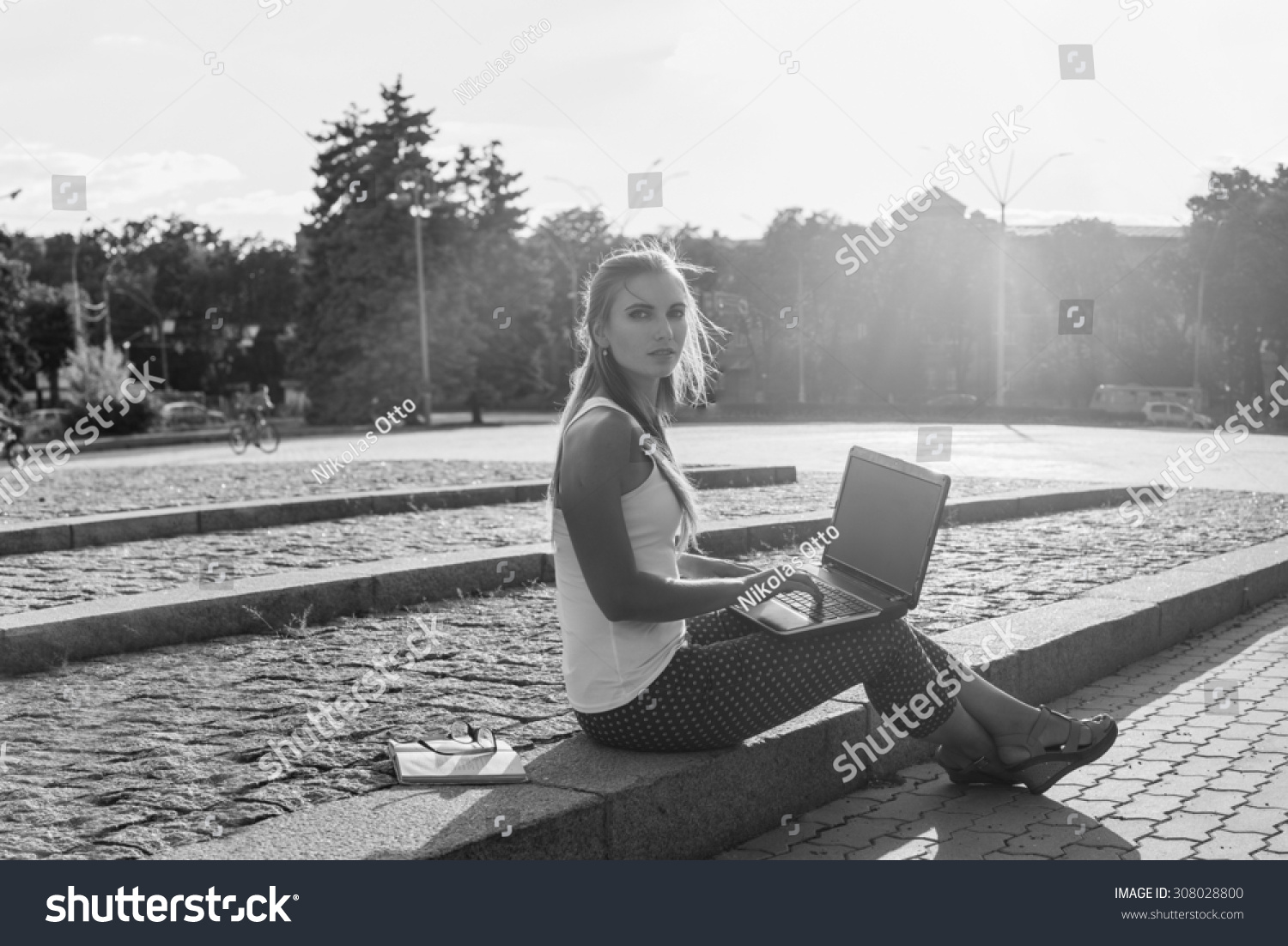 Black and White. BW. Student sitting in park near the grass working on laptop at campus