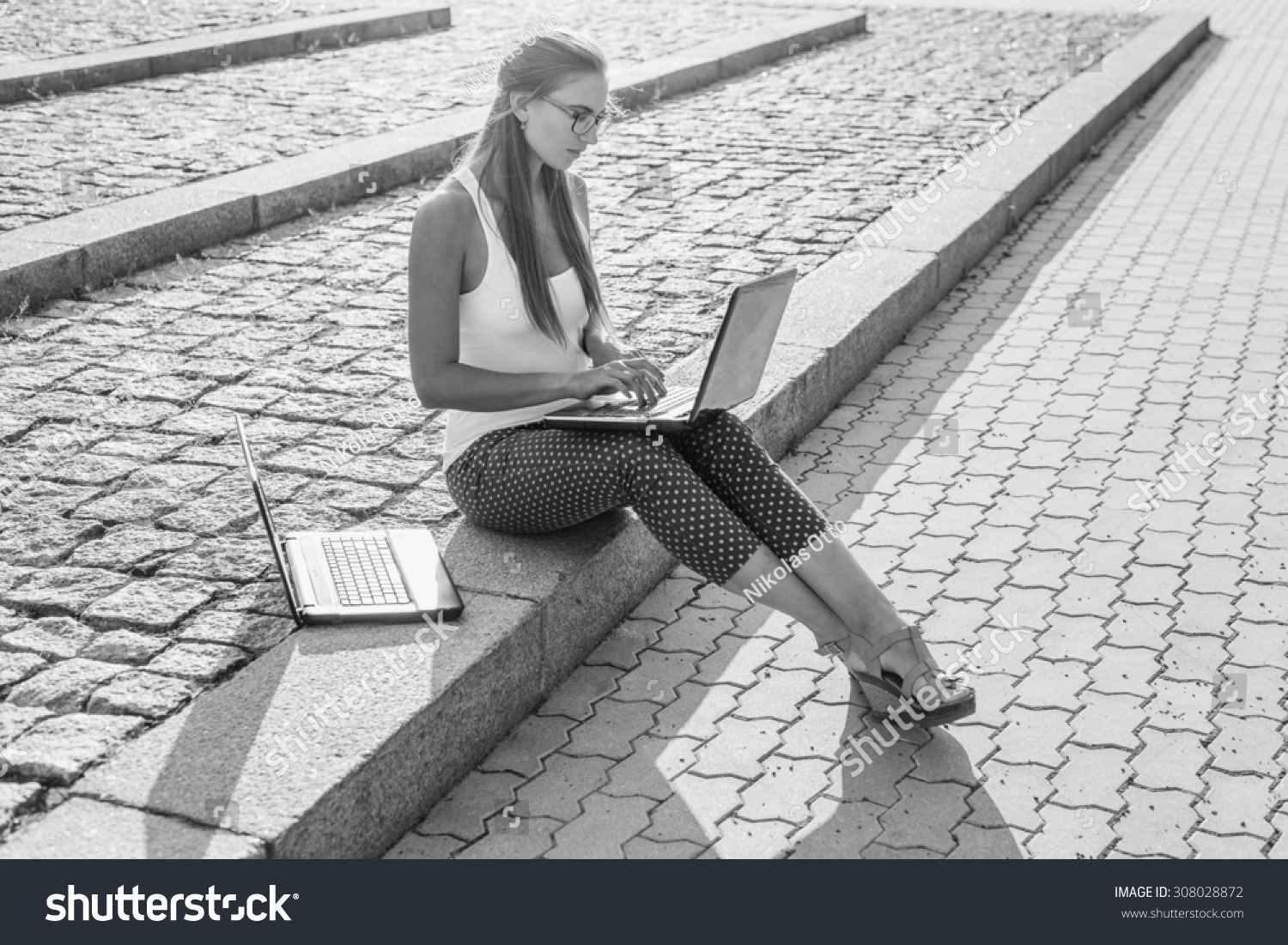 Black and White. BW. Student sitting in park near the grass working on laptop at campus
