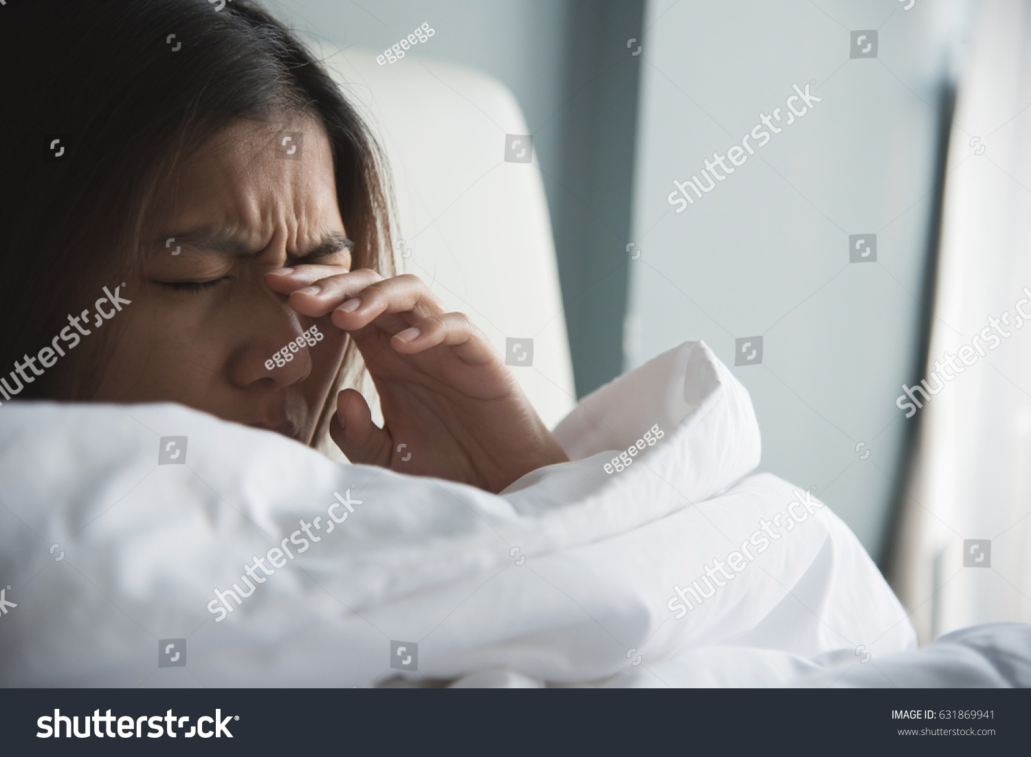 Asian woman rubbing eyes with her hand on her bed. Copy space.
